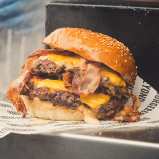a large burger stuffed with two patties, two slices of cheese, and bacon